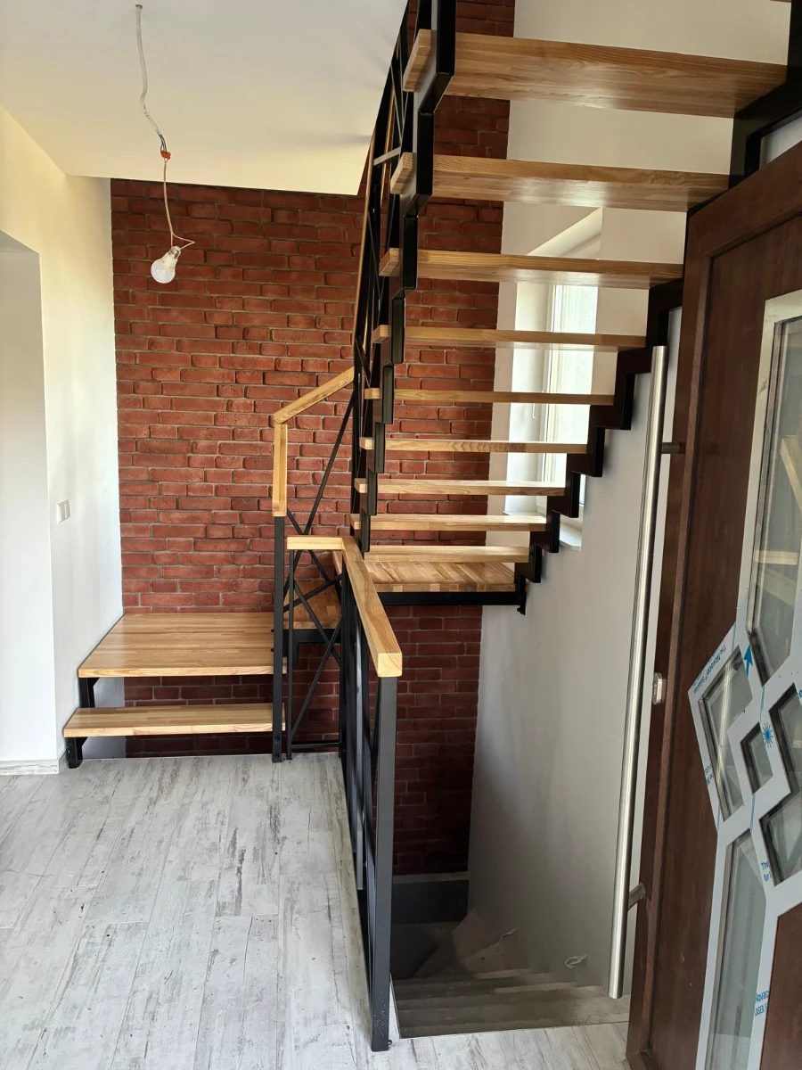 Nowoczesne schody drewniane na metalowej konstrukcji i ceglana ściana remont mieszkania
