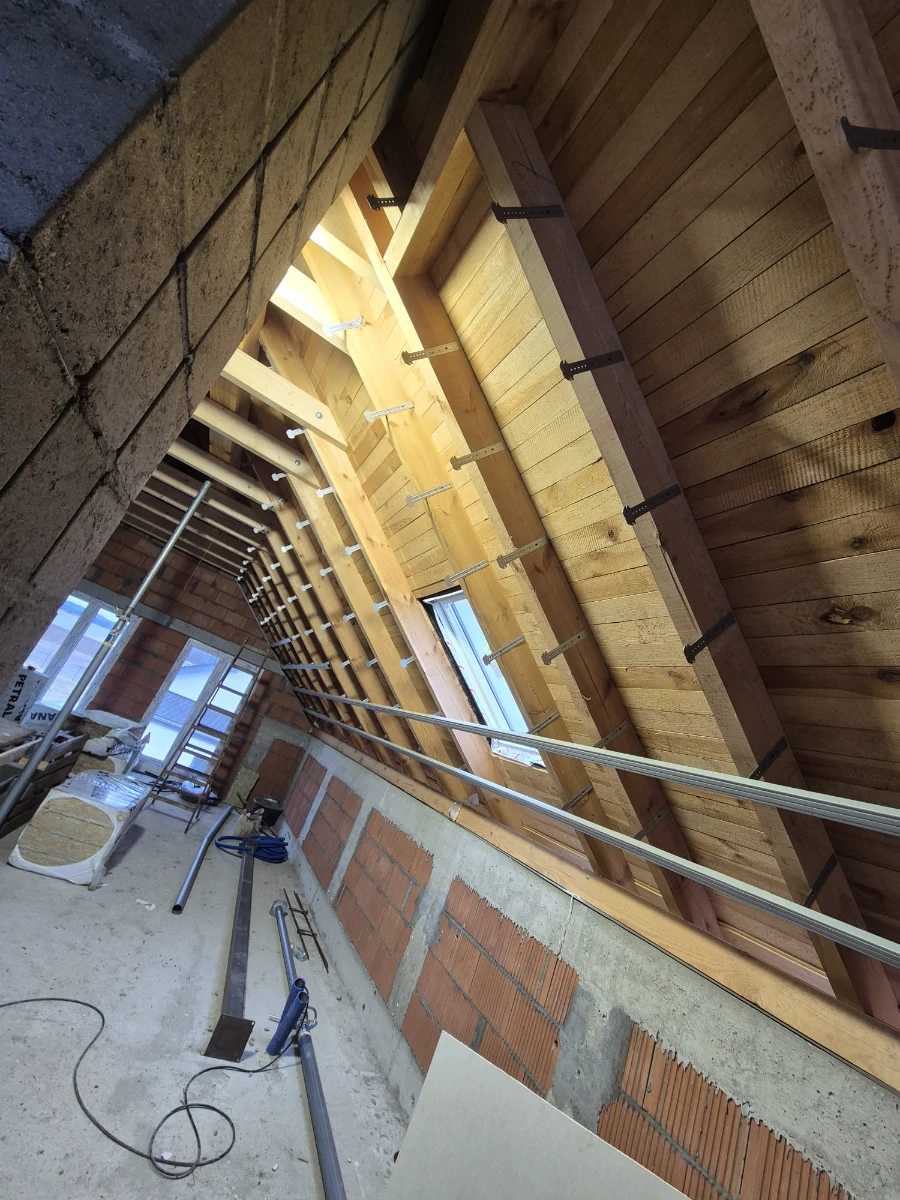 Zabudowa poddasza z widocznymi stelażami metalowymi i deskowaniem dachu pod montaż płyt GK